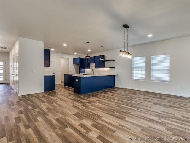 kitchen with kitchen peninsula, blue cabinetry, tasteful backsplash, wood-type flooring, and a breakfast bar area