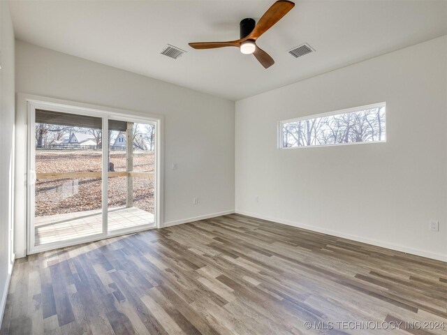 spare room featuring ceiling fan, wood-type flooring, and a wealth of natural light