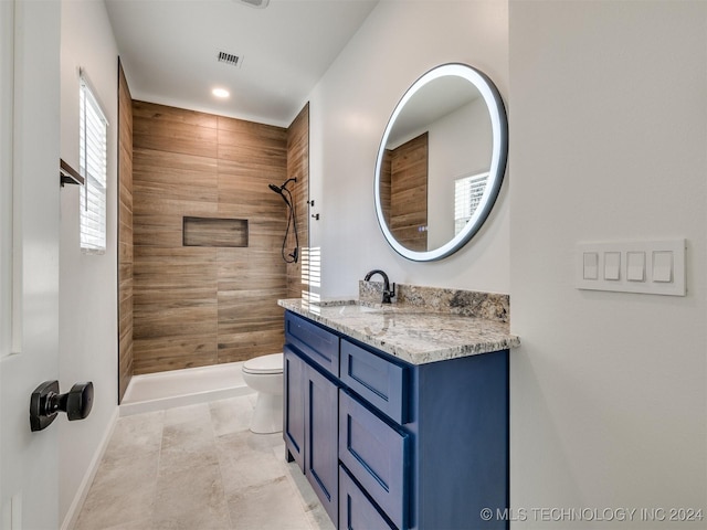 bathroom with tile patterned floors, vanity, toilet, and a tile shower