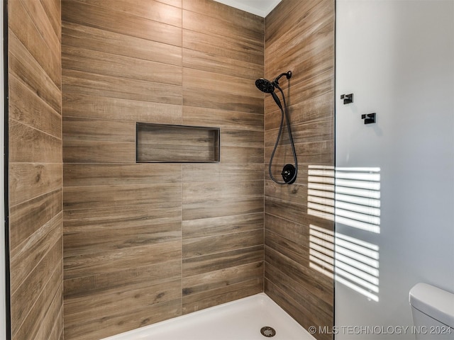 bathroom with a tile shower and toilet