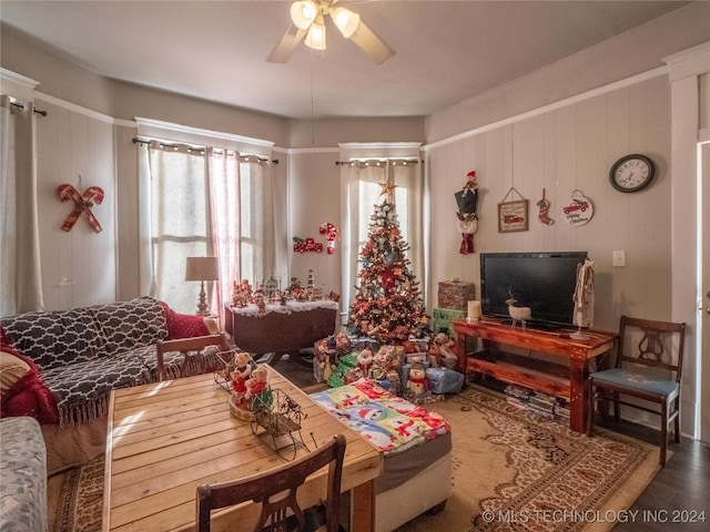 living room with plenty of natural light, ceiling fan, and wooden walls