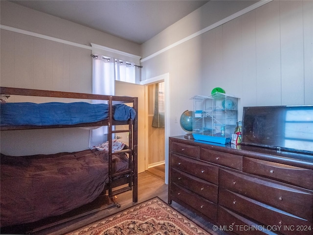 bedroom with hardwood / wood-style flooring and wooden walls