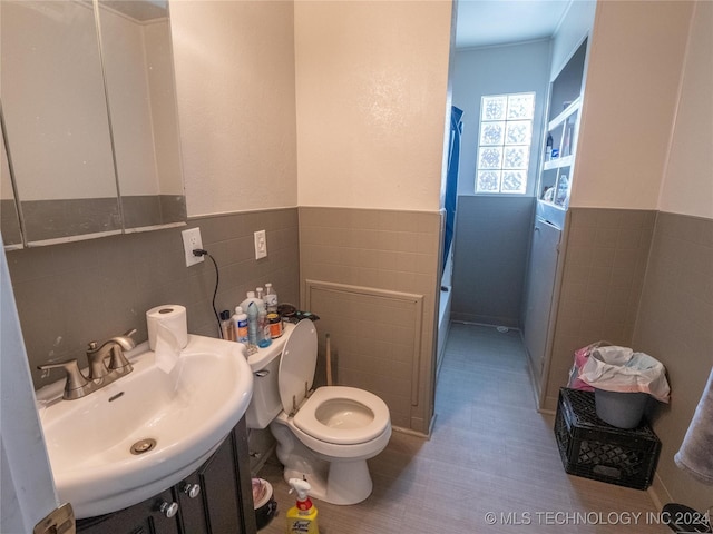 bathroom featuring toilet, sink, and tile walls