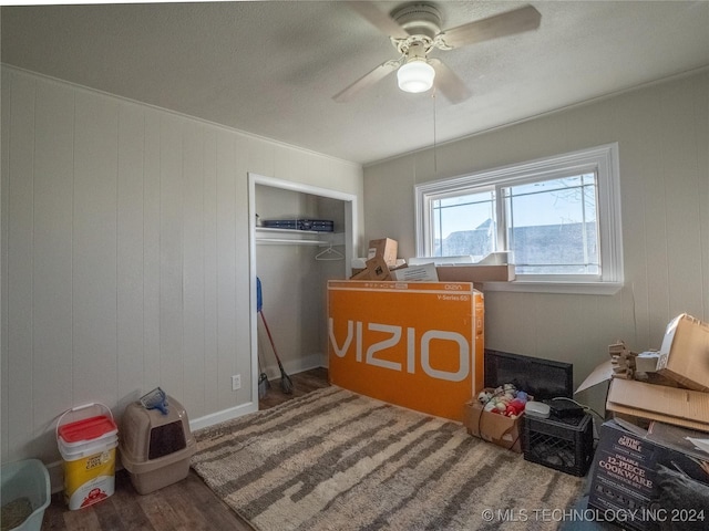 bedroom featuring ceiling fan, wood walls, wood-type flooring, and a closet