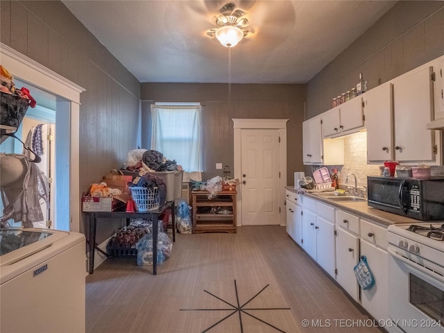 kitchen featuring white range with gas stovetop, sink, ceiling fan, white cabinetry, and washer / clothes dryer