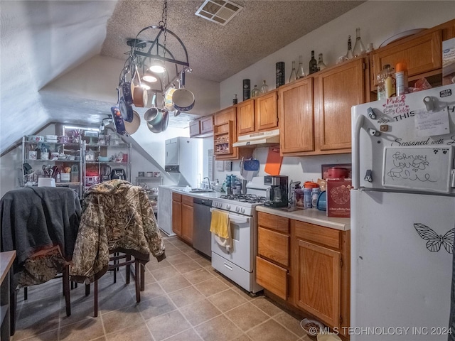 kitchen featuring a textured ceiling, white appliances, vaulted ceiling, sink, and hanging light fixtures