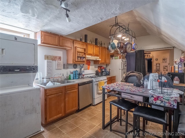 kitchen featuring sink, an inviting chandelier, stainless steel dishwasher, range with gas stovetop, and stacked washer and clothes dryer