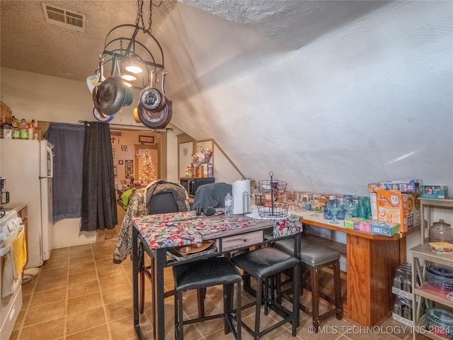 dining room with a textured ceiling and vaulted ceiling