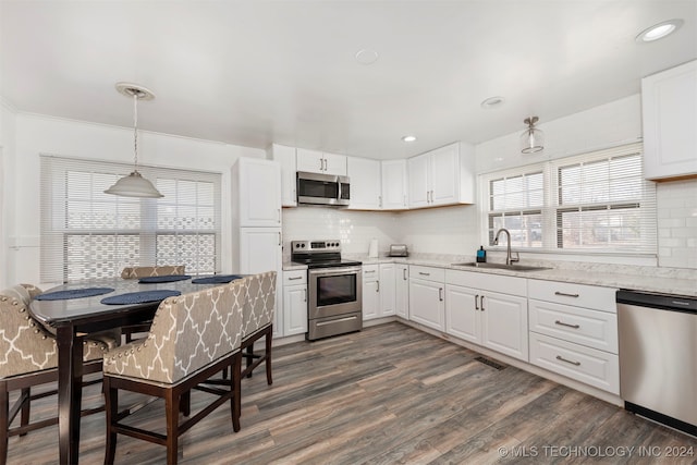 kitchen featuring white cabinetry, sink, hanging light fixtures, stainless steel appliances, and dark hardwood / wood-style floors