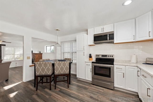 kitchen featuring dark hardwood / wood-style flooring, white cabinetry, stainless steel appliances, and hanging light fixtures