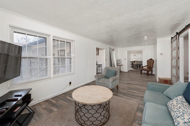 living room with crown molding, a barn door, dark hardwood / wood-style flooring, and a textured ceiling