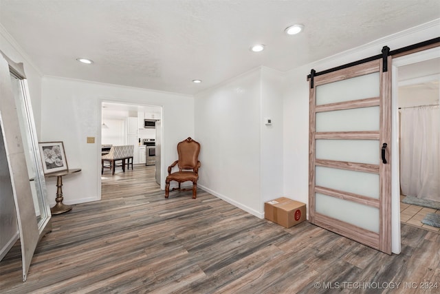 sitting room featuring a barn door, dark hardwood / wood-style flooring, and crown molding