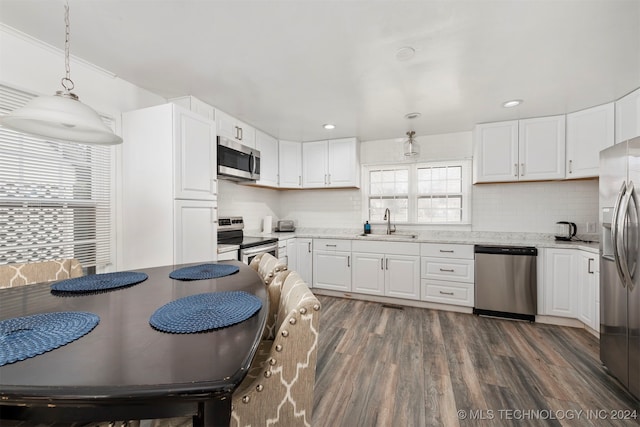 kitchen with appliances with stainless steel finishes, dark hardwood / wood-style flooring, tasteful backsplash, pendant lighting, and white cabinets