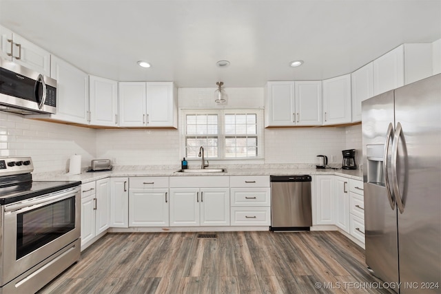 kitchen featuring appliances with stainless steel finishes, light stone counters, sink, dark hardwood / wood-style floors, and white cabinetry