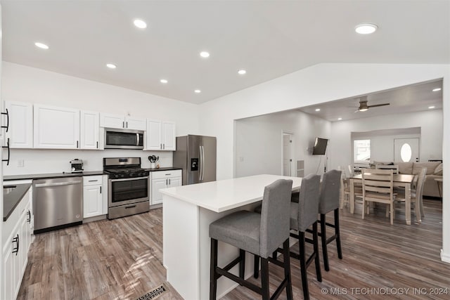 kitchen featuring a kitchen bar, appliances with stainless steel finishes, dark hardwood / wood-style flooring, ceiling fan, and white cabinetry