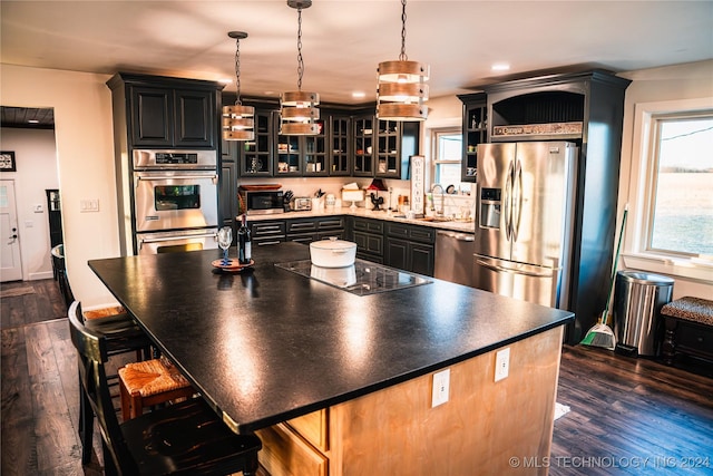 kitchen featuring pendant lighting, a center island, dark wood-type flooring, and appliances with stainless steel finishes