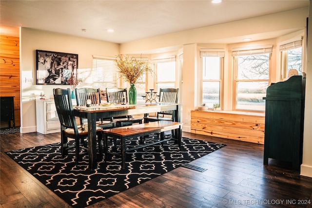 dining room featuring dark wood-type flooring and wood walls