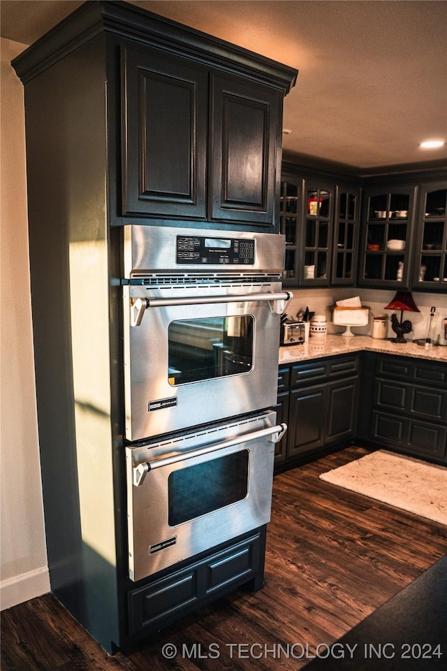 kitchen with stainless steel double oven and dark hardwood / wood-style floors