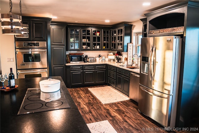 kitchen with light stone countertops, sink, stainless steel appliances, dark hardwood / wood-style flooring, and pendant lighting