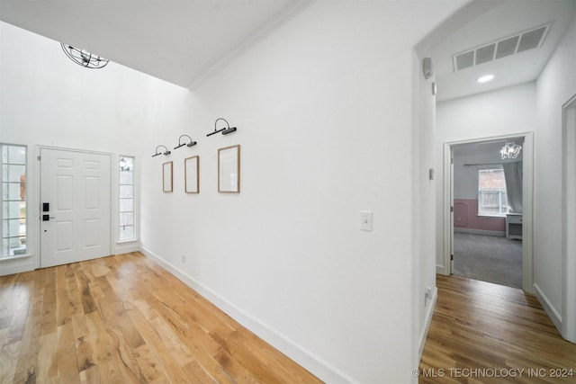 foyer featuring a notable chandelier, ornamental molding, and wood-type flooring