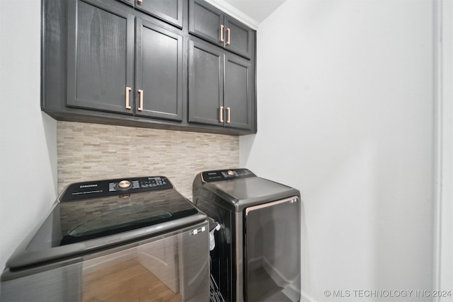 clothes washing area featuring washing machine and dryer and cabinets