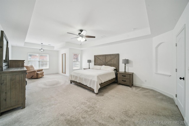 bedroom featuring ceiling fan, a raised ceiling, and light colored carpet