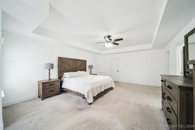 bedroom featuring ceiling fan, light carpet, and a tray ceiling