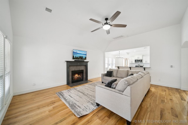 living room featuring ceiling fan with notable chandelier, a wealth of natural light, and light wood-type flooring