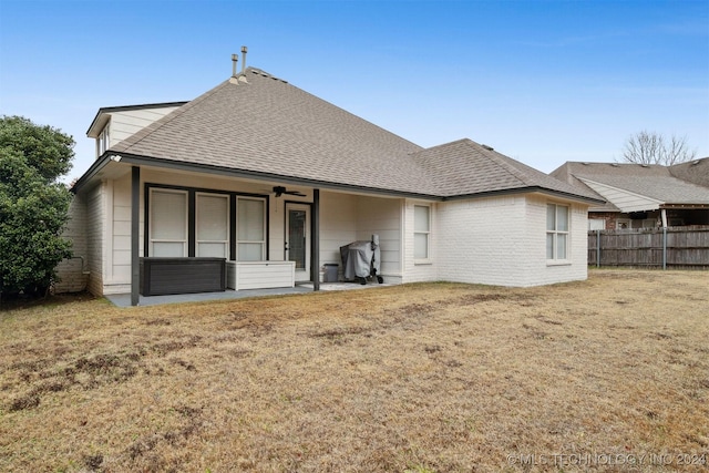 rear view of house featuring ceiling fan and a lawn