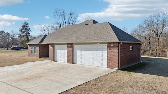 view of property exterior featuring an outbuilding, brick siding, and roof with shingles