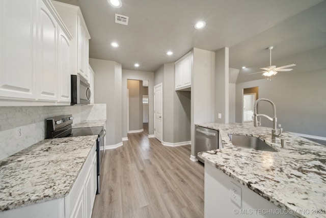 kitchen featuring visible vents, light wood-style flooring, stainless steel appliances, white cabinetry, and a sink