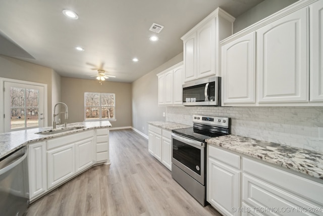 kitchen featuring visible vents, light wood-style flooring, a sink, appliances with stainless steel finishes, and decorative backsplash