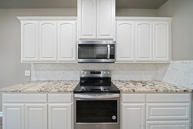 kitchen featuring decorative backsplash, appliances with stainless steel finishes, white cabinetry, and light stone countertops