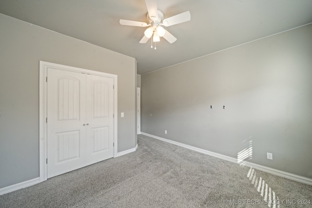 unfurnished bedroom with a closet, carpet flooring, a ceiling fan, and baseboards