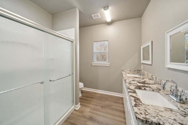 full bathroom with visible vents, toilet, a stall shower, a sink, and wood finished floors