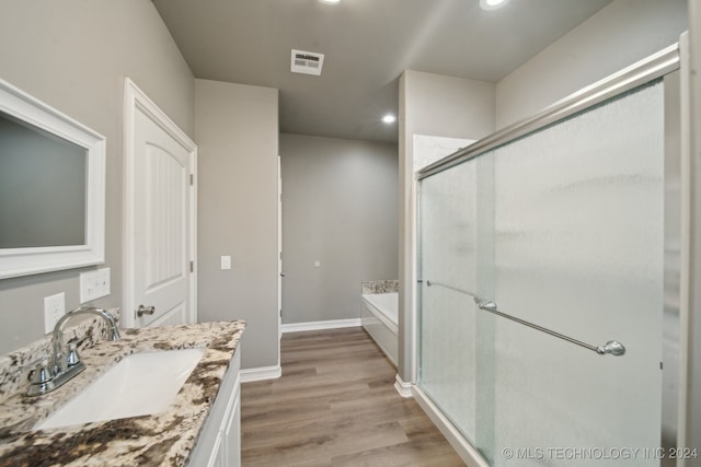 full bathroom with vanity, a shower stall, a garden tub, and wood finished floors