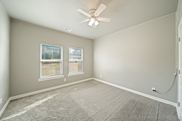 carpeted empty room featuring baseboards, visible vents, and ceiling fan