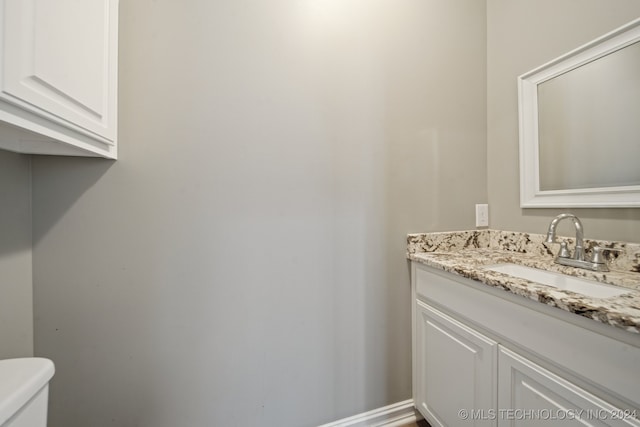 bathroom featuring vanity, toilet, and baseboards