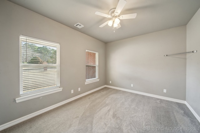 unfurnished room featuring carpet, baseboards, visible vents, and ceiling fan