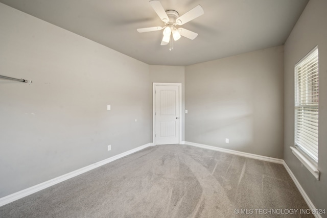 carpeted empty room with ceiling fan and baseboards