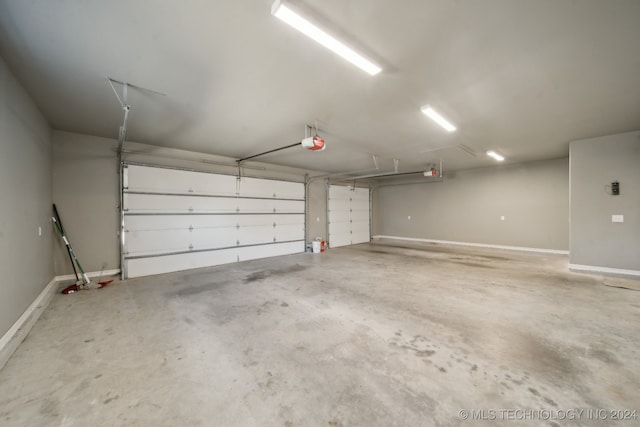 parking garage featuring baseboards and a garage door opener