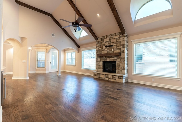 unfurnished living room with high vaulted ceiling, a fireplace, beamed ceiling, ceiling fan, and dark wood-type flooring