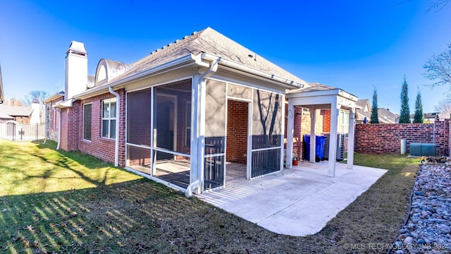 back of house featuring a sunroom, a patio area, and a lawn