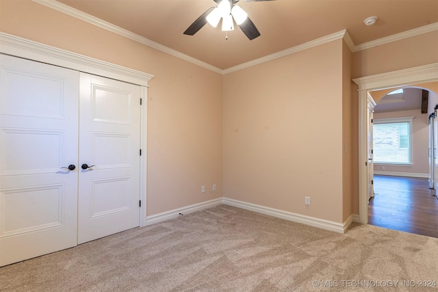 unfurnished room with crown molding, light colored carpet, and ceiling fan