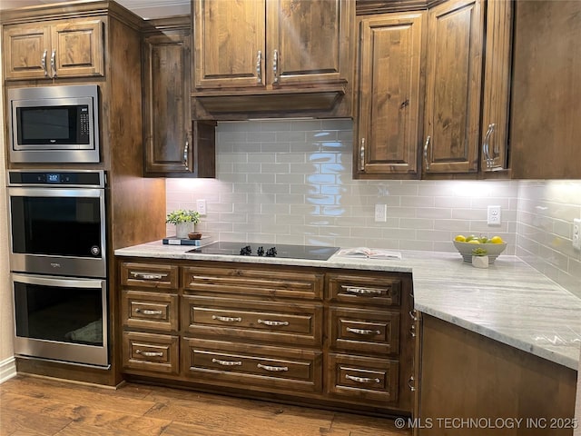 kitchen featuring light stone countertops, appliances with stainless steel finishes, dark hardwood / wood-style floors, and backsplash