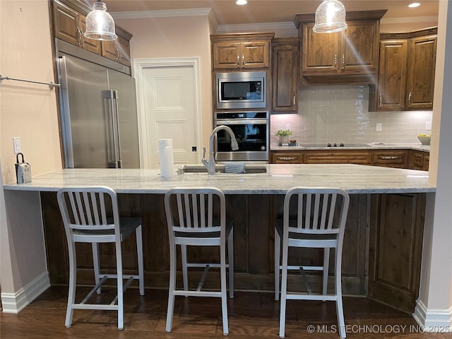 kitchen featuring built in appliances, a breakfast bar area, and tasteful backsplash