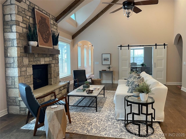 living room featuring a barn door, dark wood-type flooring, high vaulted ceiling, and beam ceiling