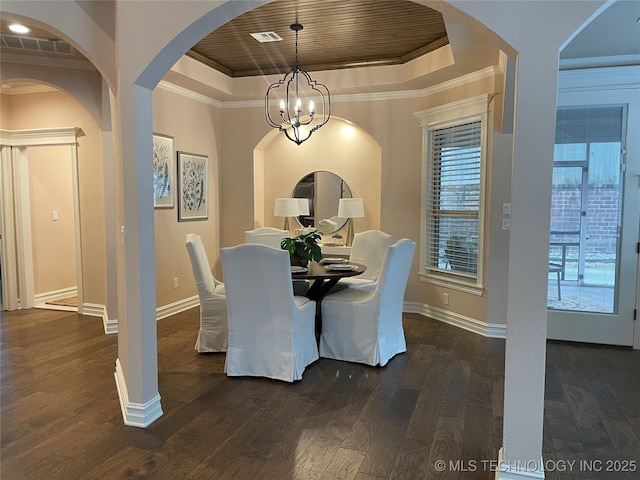 dining room with dark wood-type flooring, a tray ceiling, a chandelier, and crown molding