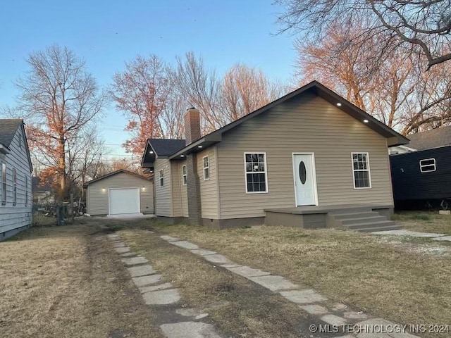 view of front of home with a garage, an outbuilding, and a front yard