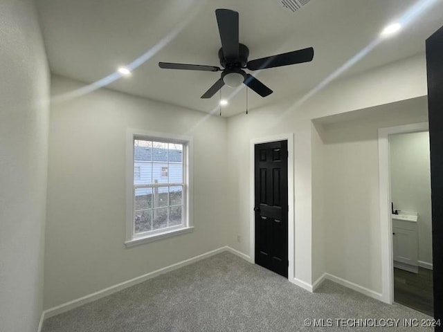 unfurnished bedroom with ceiling fan, light colored carpet, and ensuite bathroom